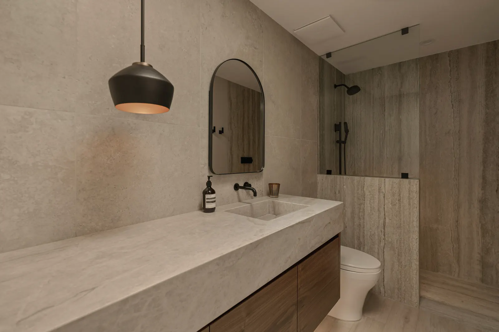 A long stone vanity beside a walk-in shower