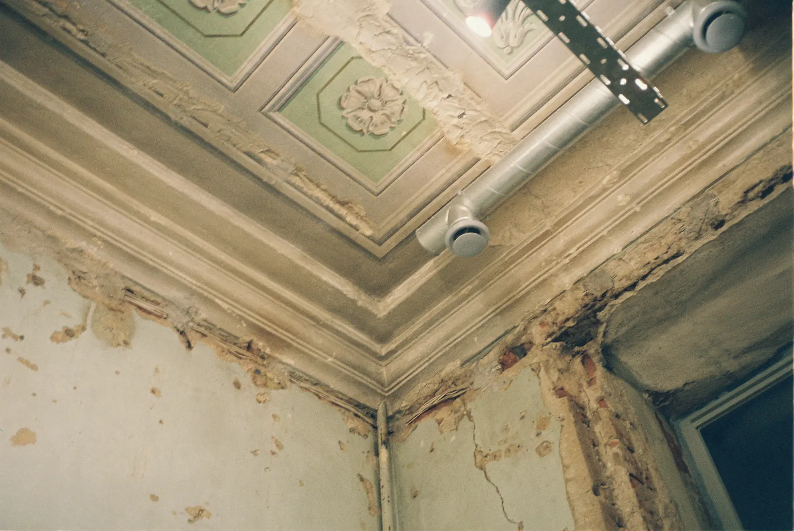 A water-stained ceiling corner with peeling paint