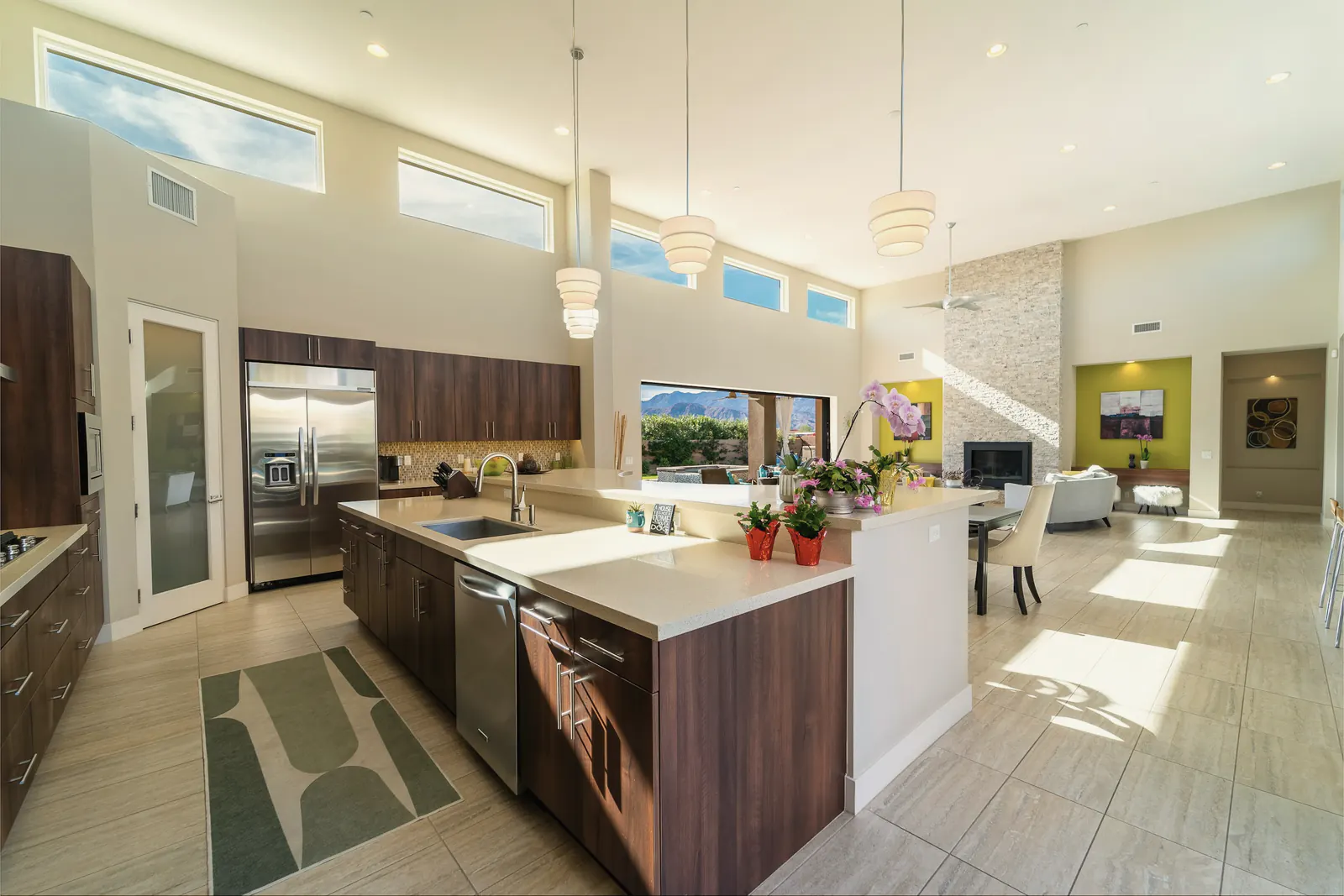 A kitchen with a walnut and quartz island under a wood ceiling