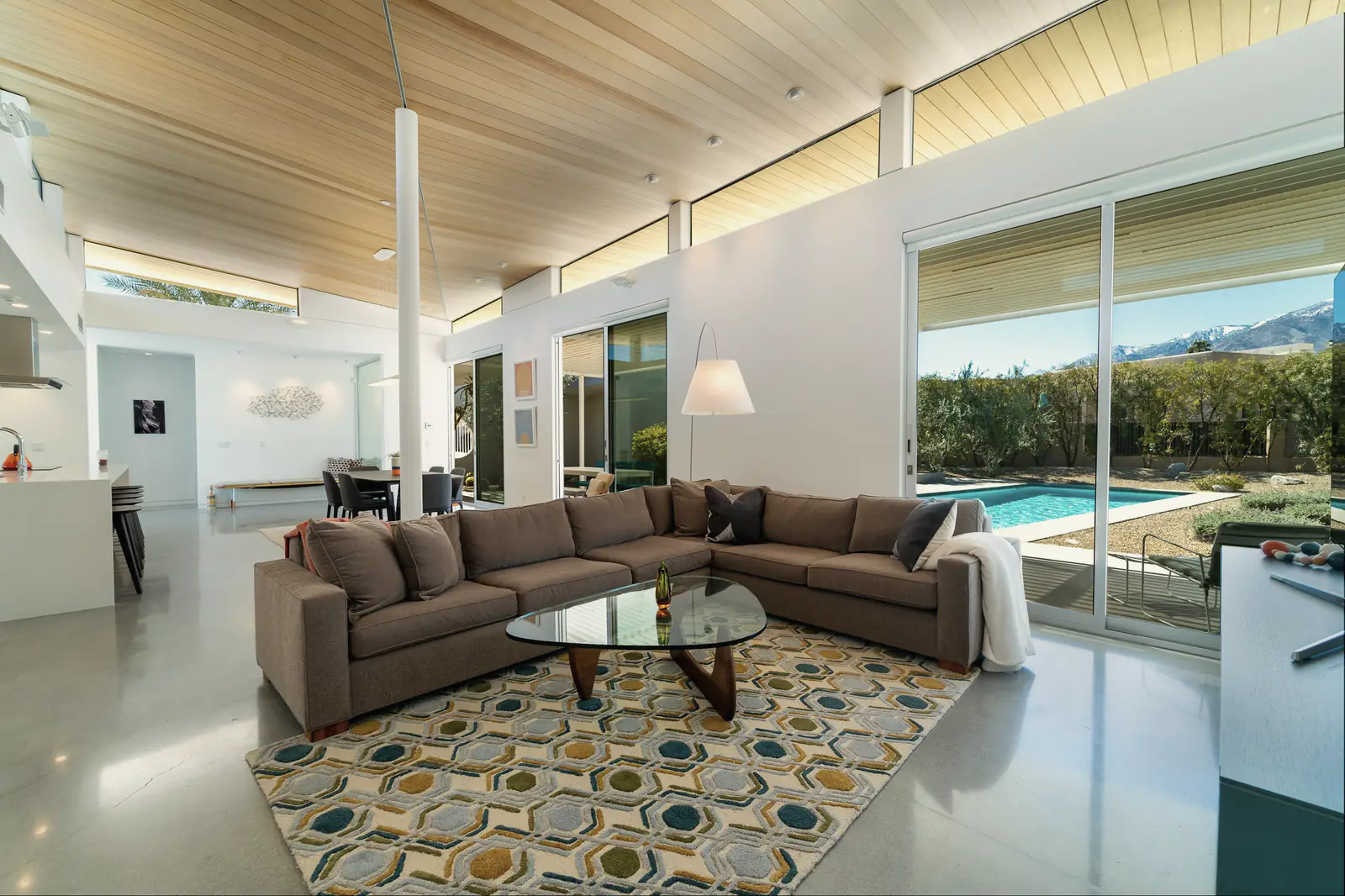 A living room with tall glass looking out to a desert garden