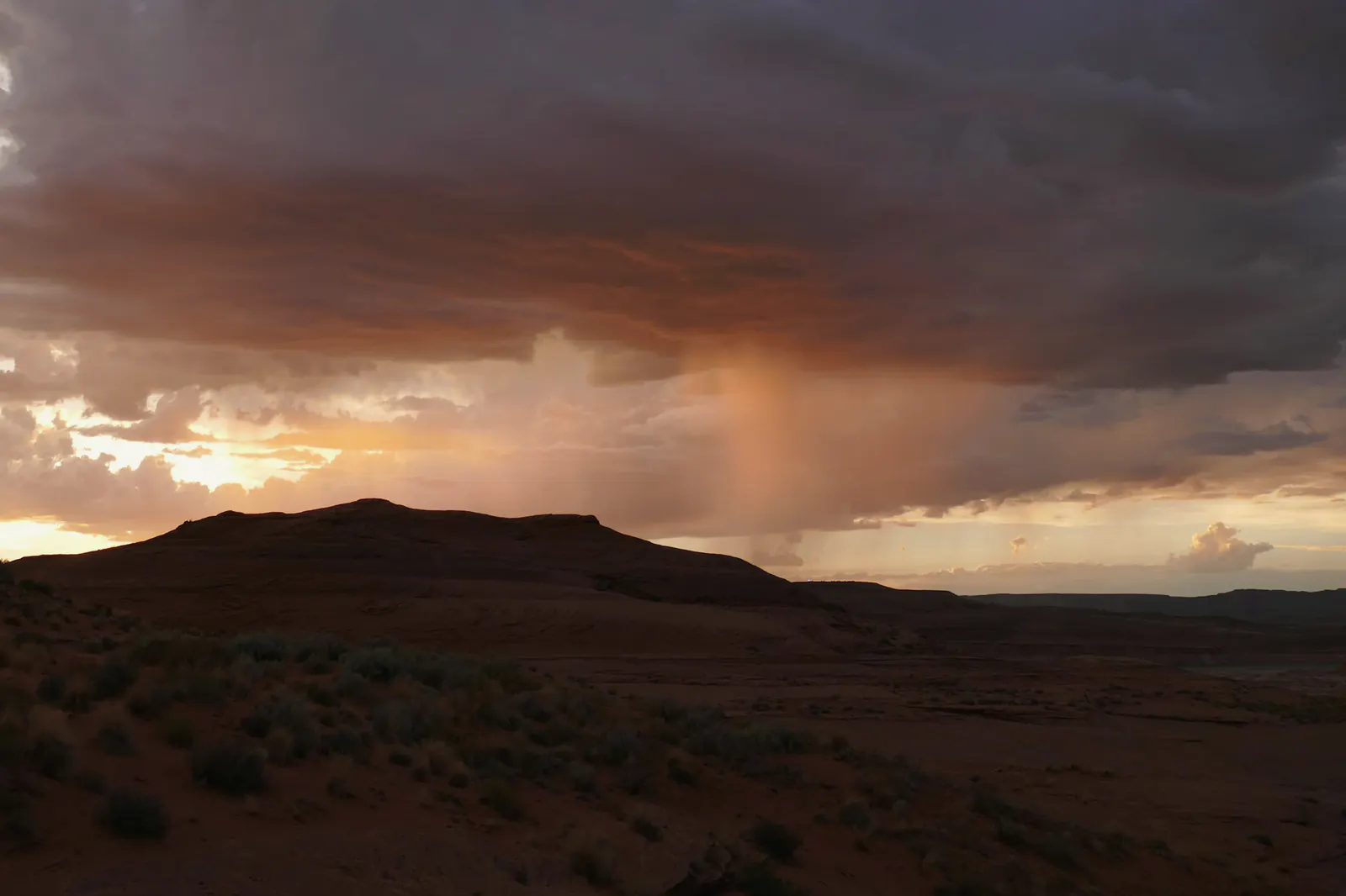 A monsoon storm breaking over desert hills at sunset