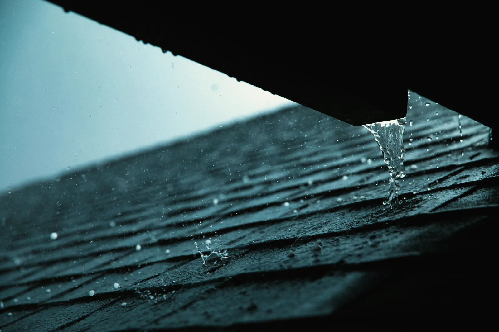 Rain running off the edge of a shingle roof